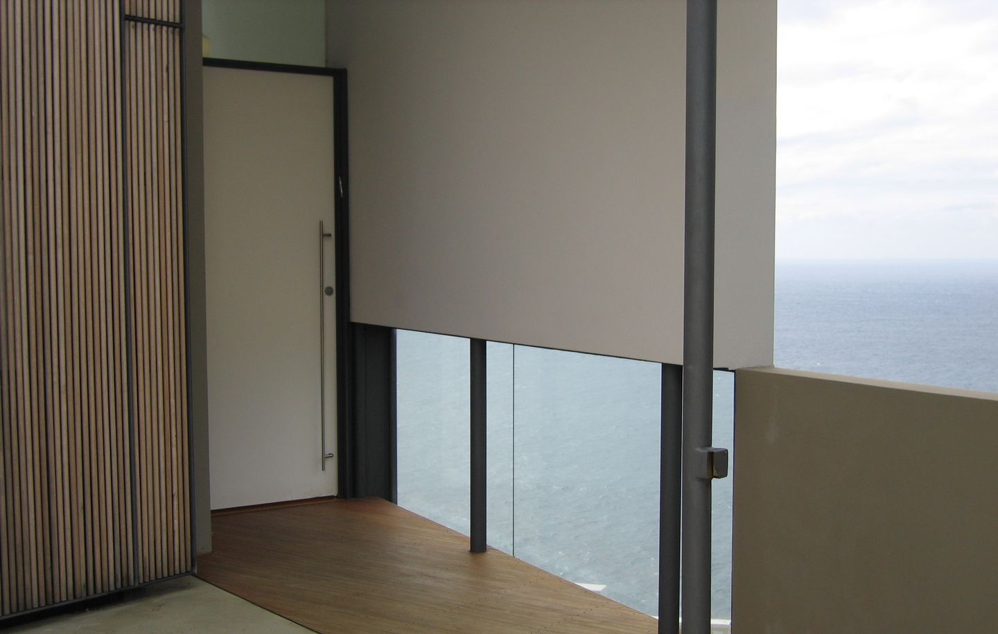 Holman House  White painted entry door with frameless glass framing view of ocean in cliff house in Dover Heights Sydney designed by Durbach Block Jaggers Architects