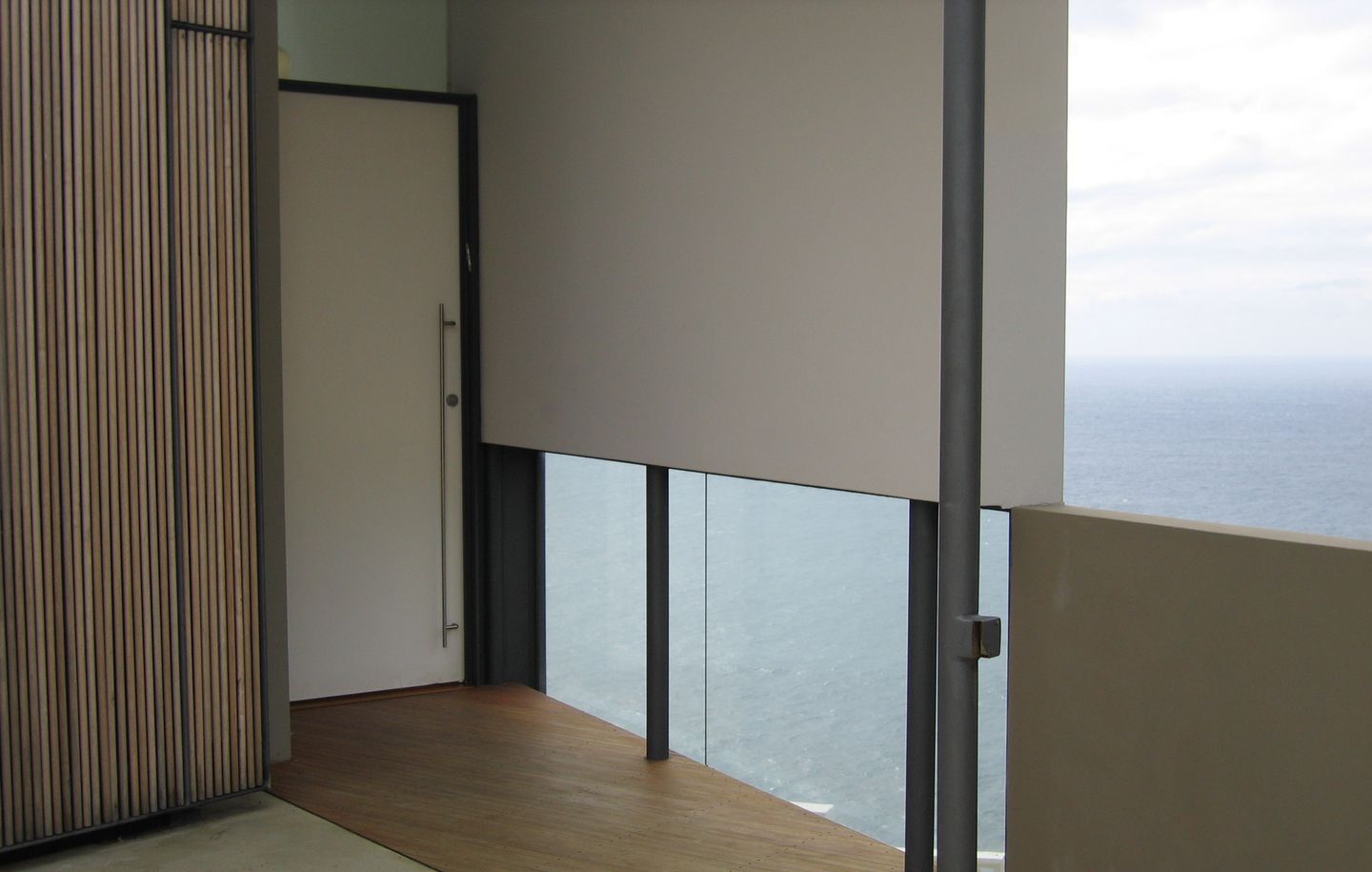 White painted entry door with frameless glass framing view of ocean in cliff house in Dover Heights Sydney designed by Durbach Block Jaggers Architects
